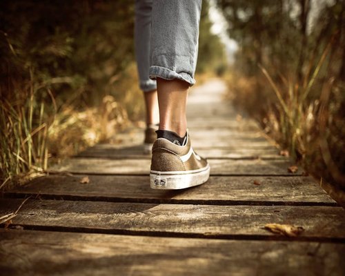 Person walking comfortably on a park path at sunset